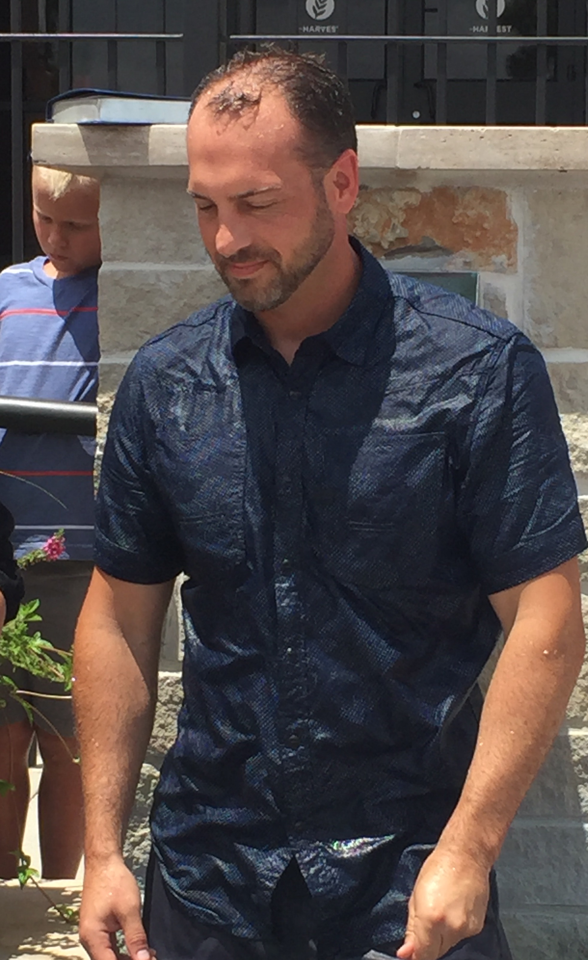 A man in a blue shirt is standing outside