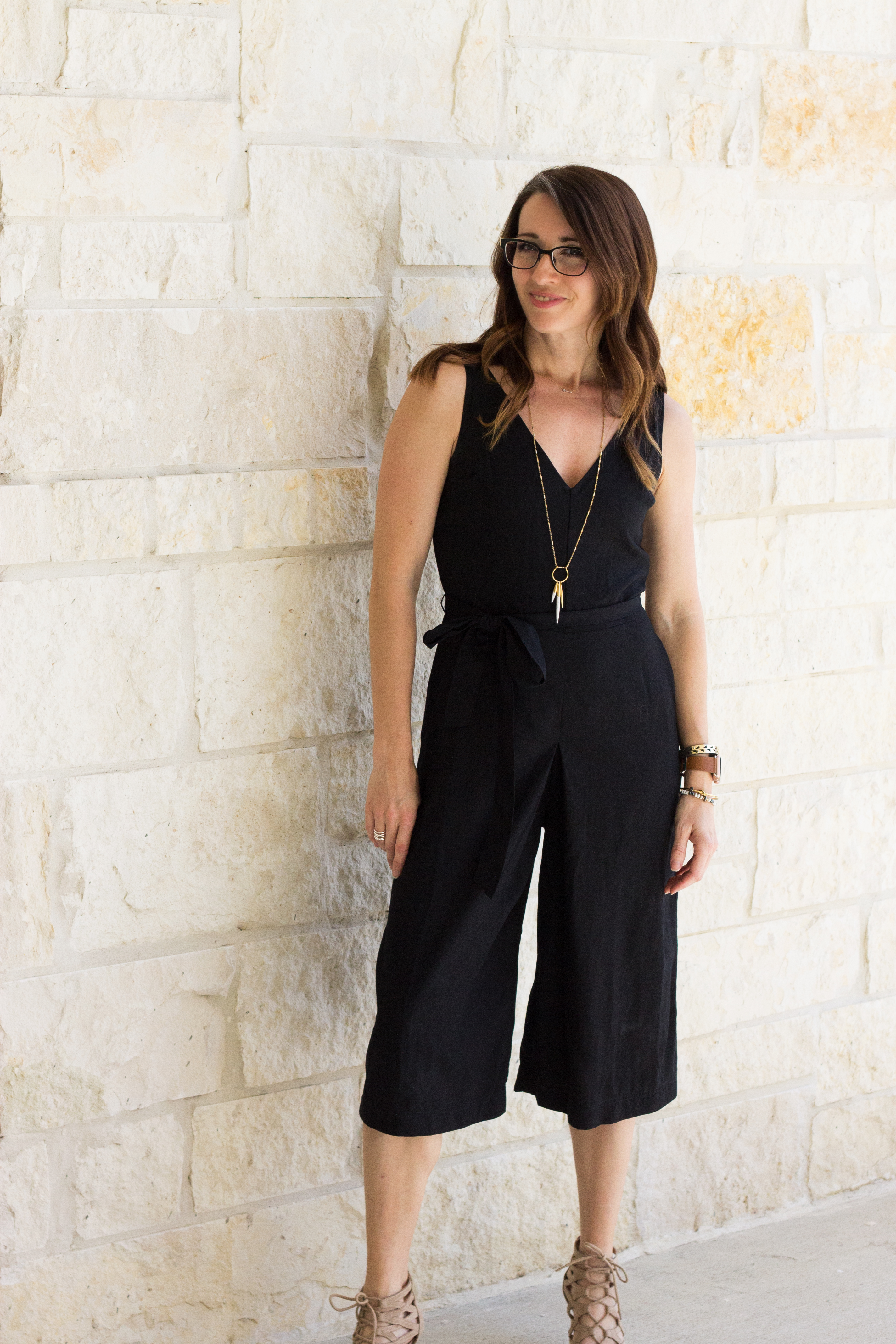 A woman standing in front of a wall wearing black.