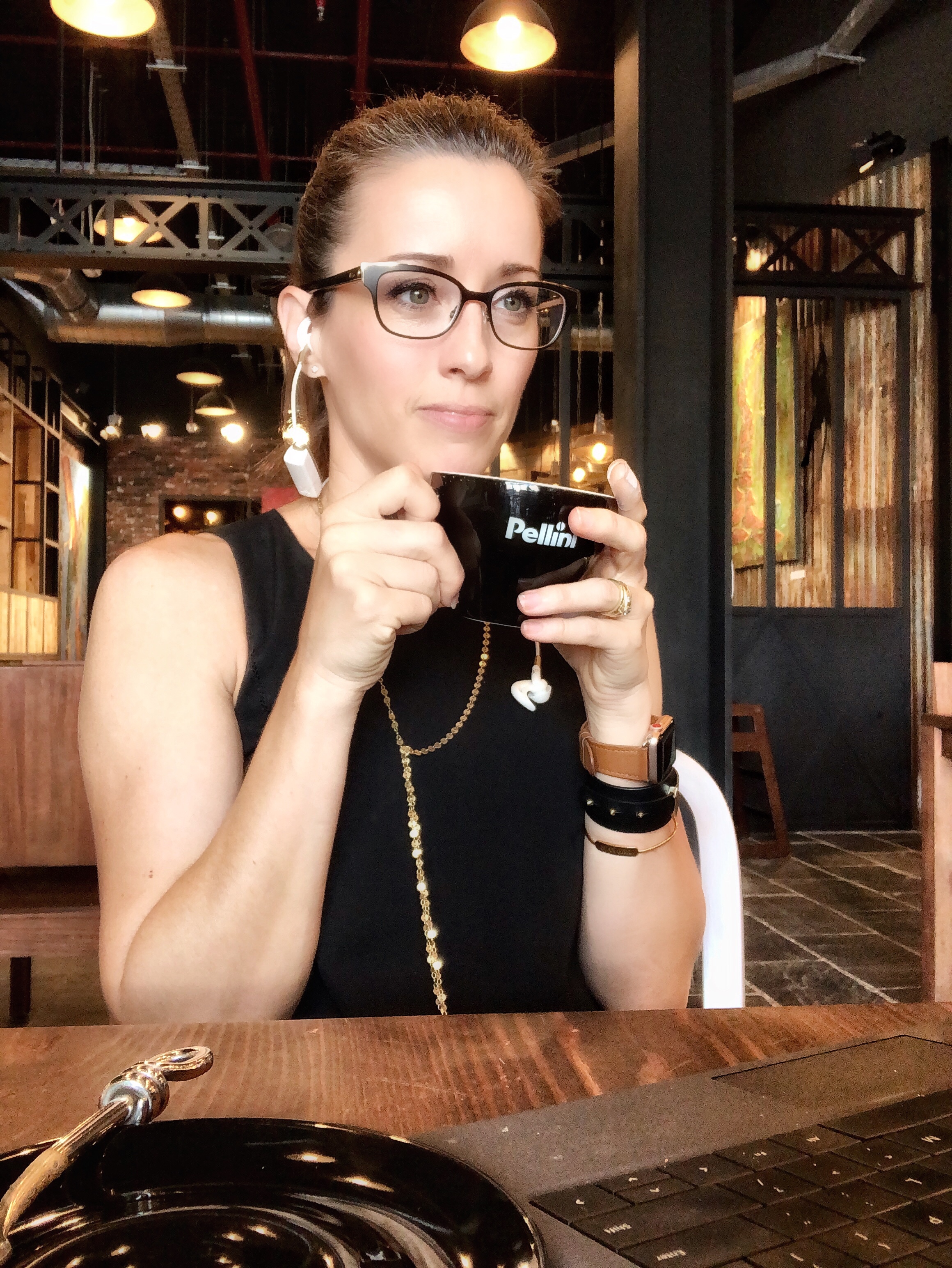 A woman holding up her phone while sitting at a table.