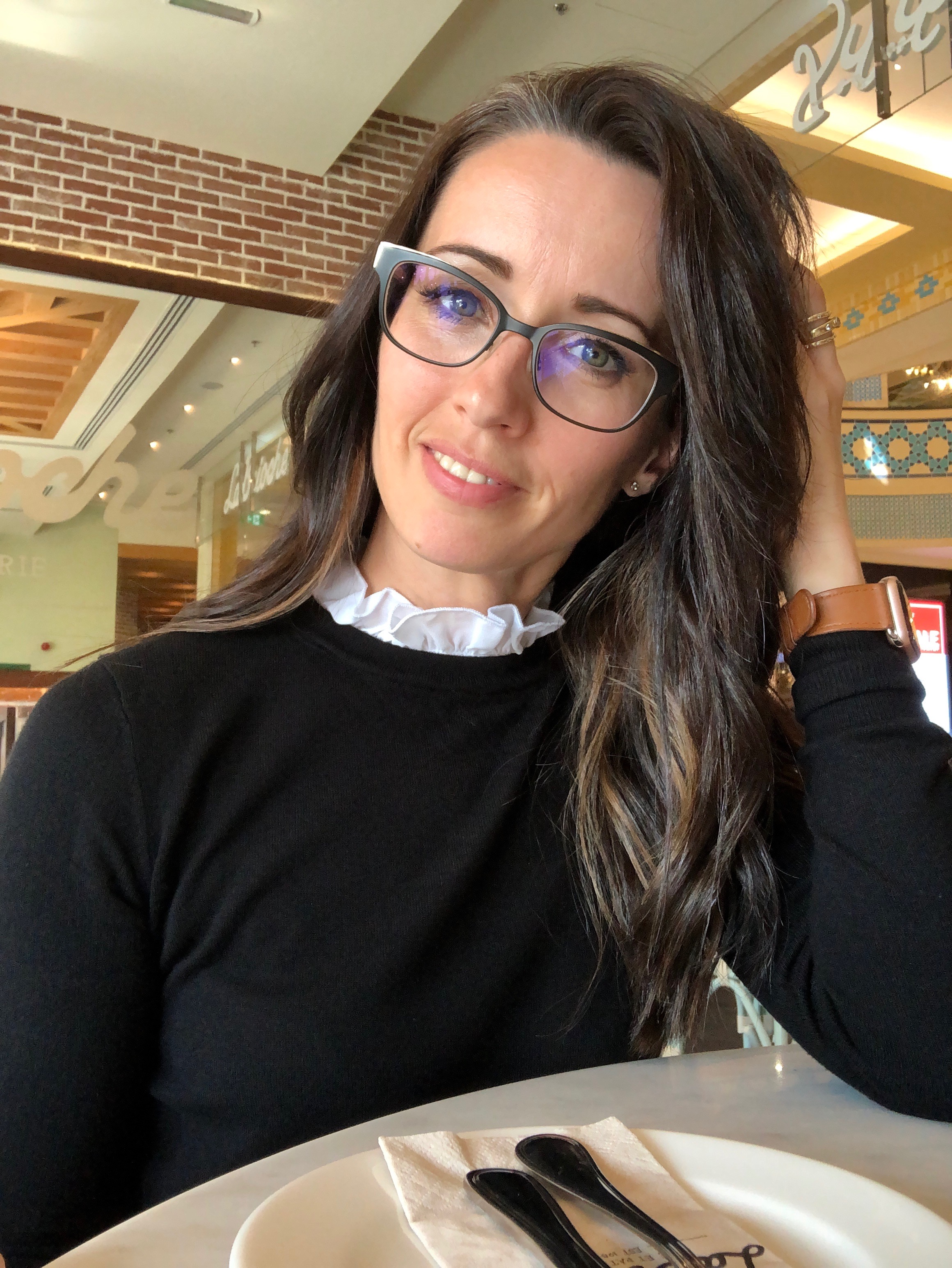 A woman with glasses and long hair wearing a black sweater.