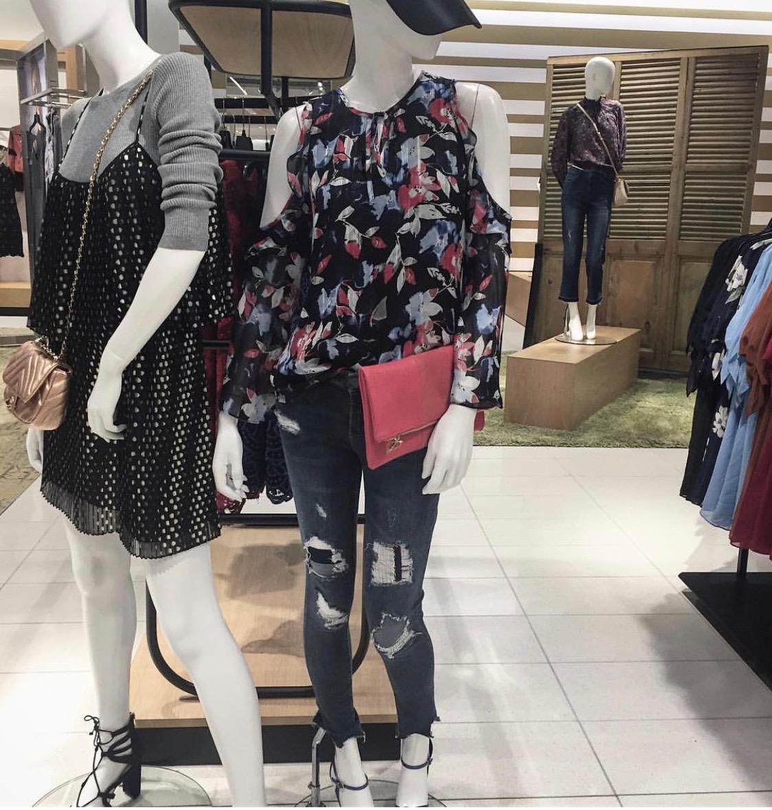 Two mannequins in a store with clothing on display.