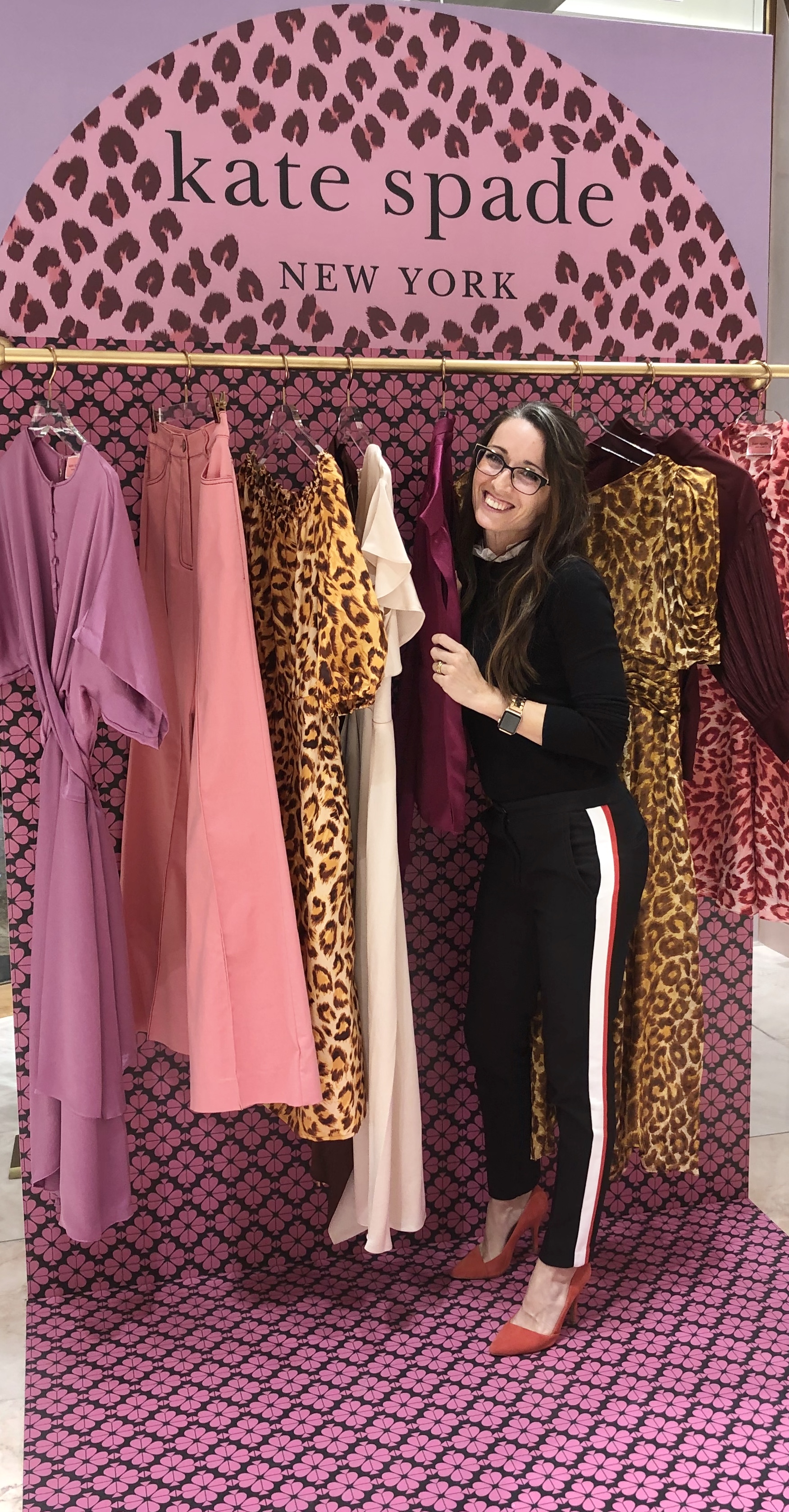 A woman standing next to some clothes on a rack