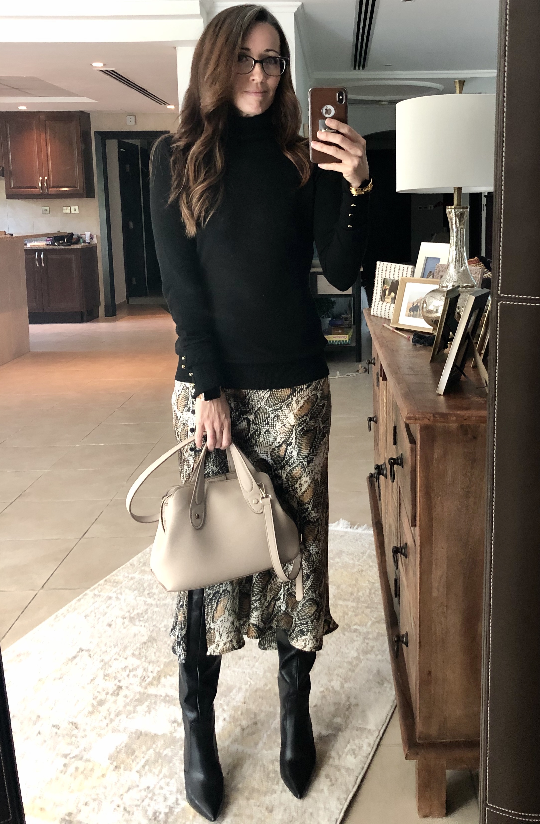 A woman standing in front of a mirror holding onto a purse.