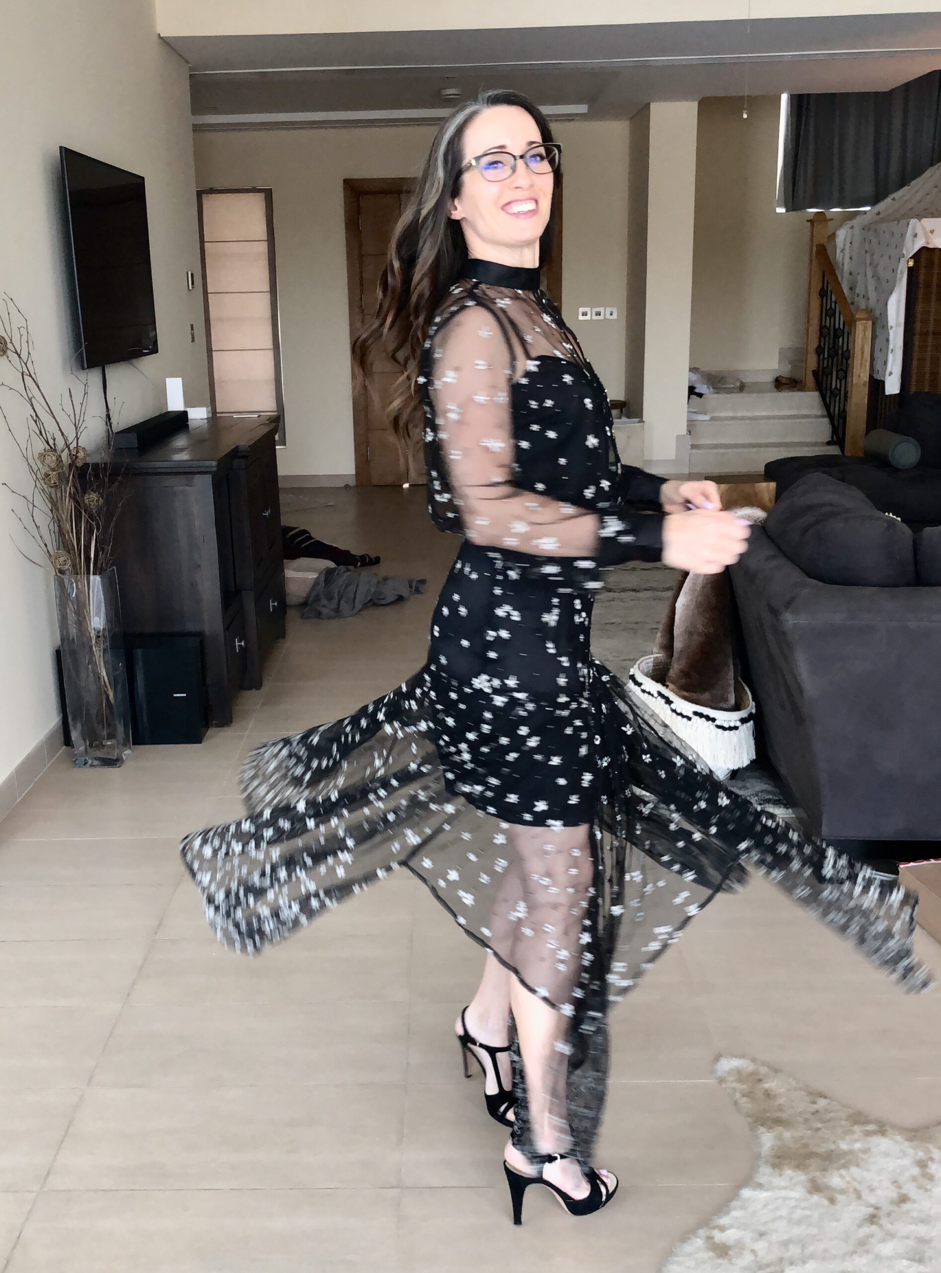 A woman in black dress dancing on the floor.