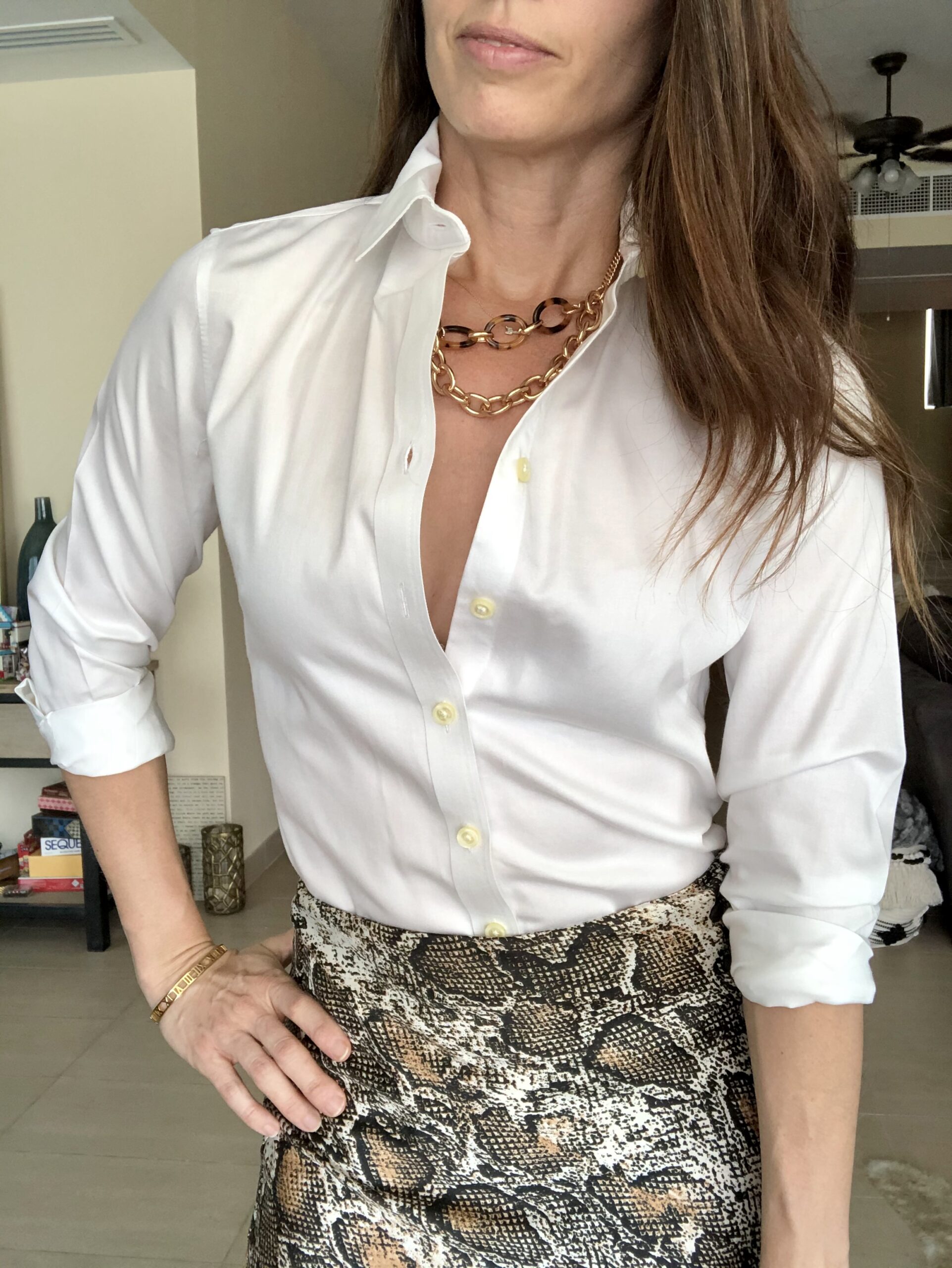 A woman wearing a white shirt and animal print skirt.