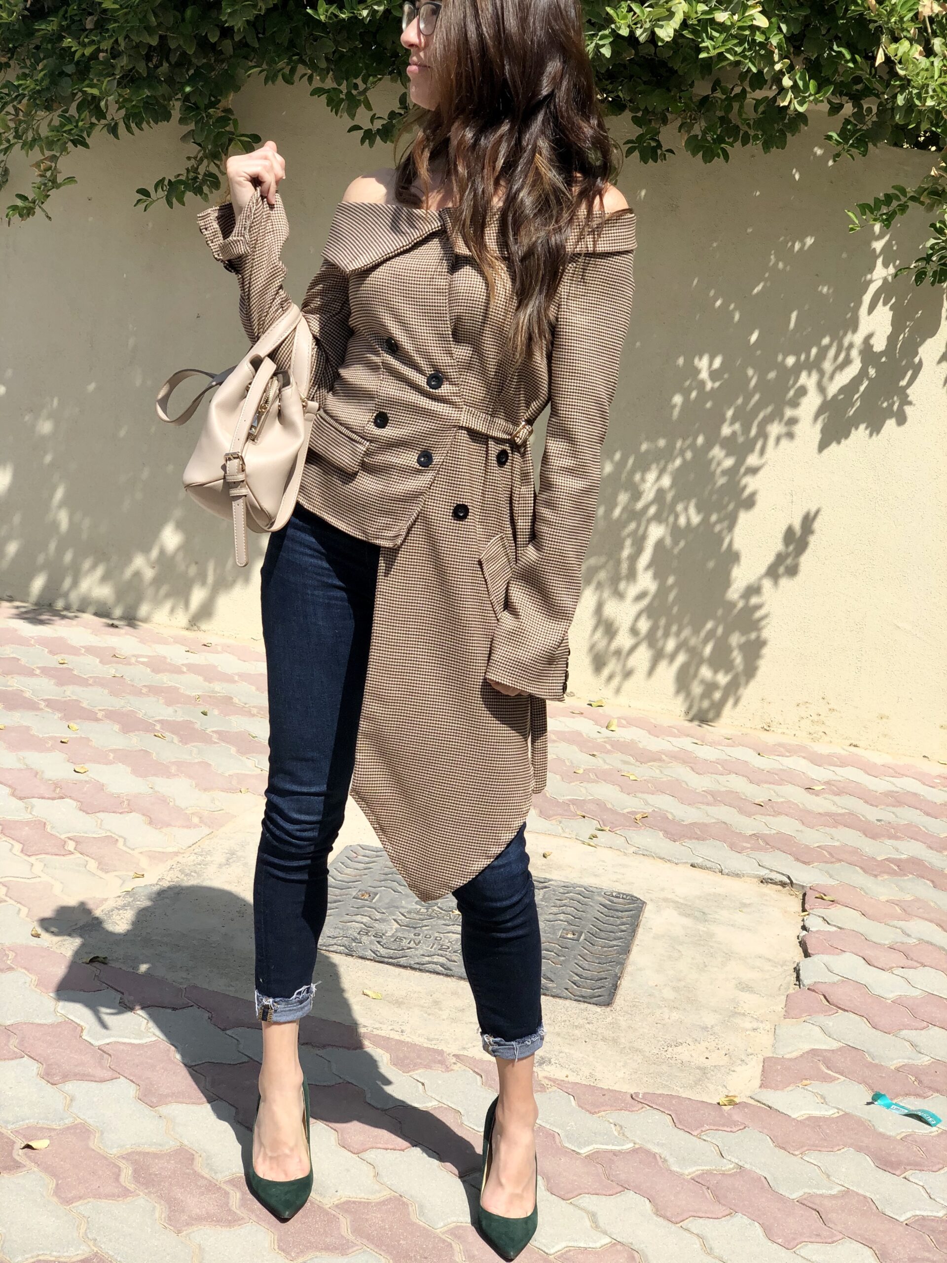 A woman in a tan coat and jeans.