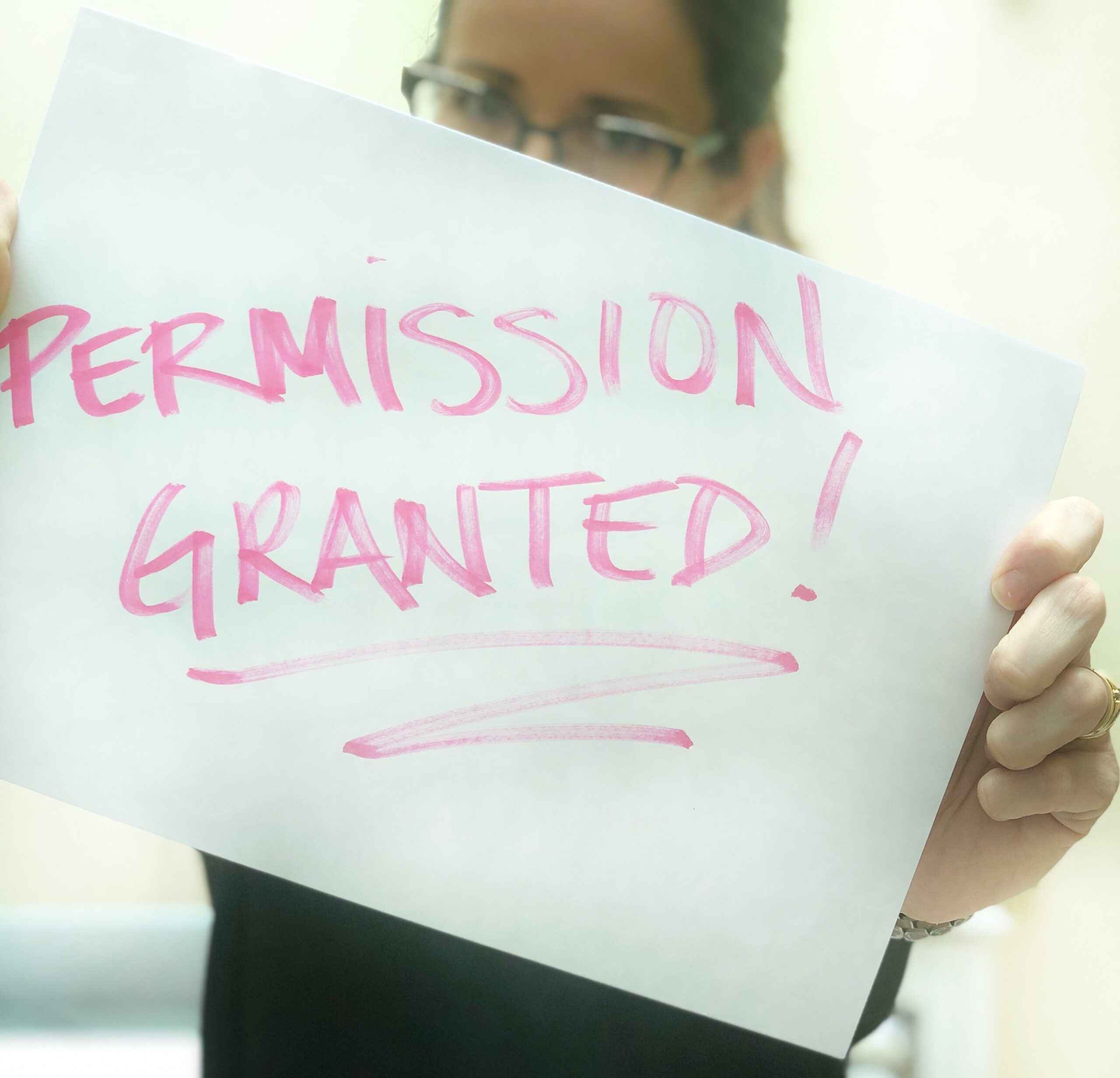 A person holding up a sign that says permission granted.