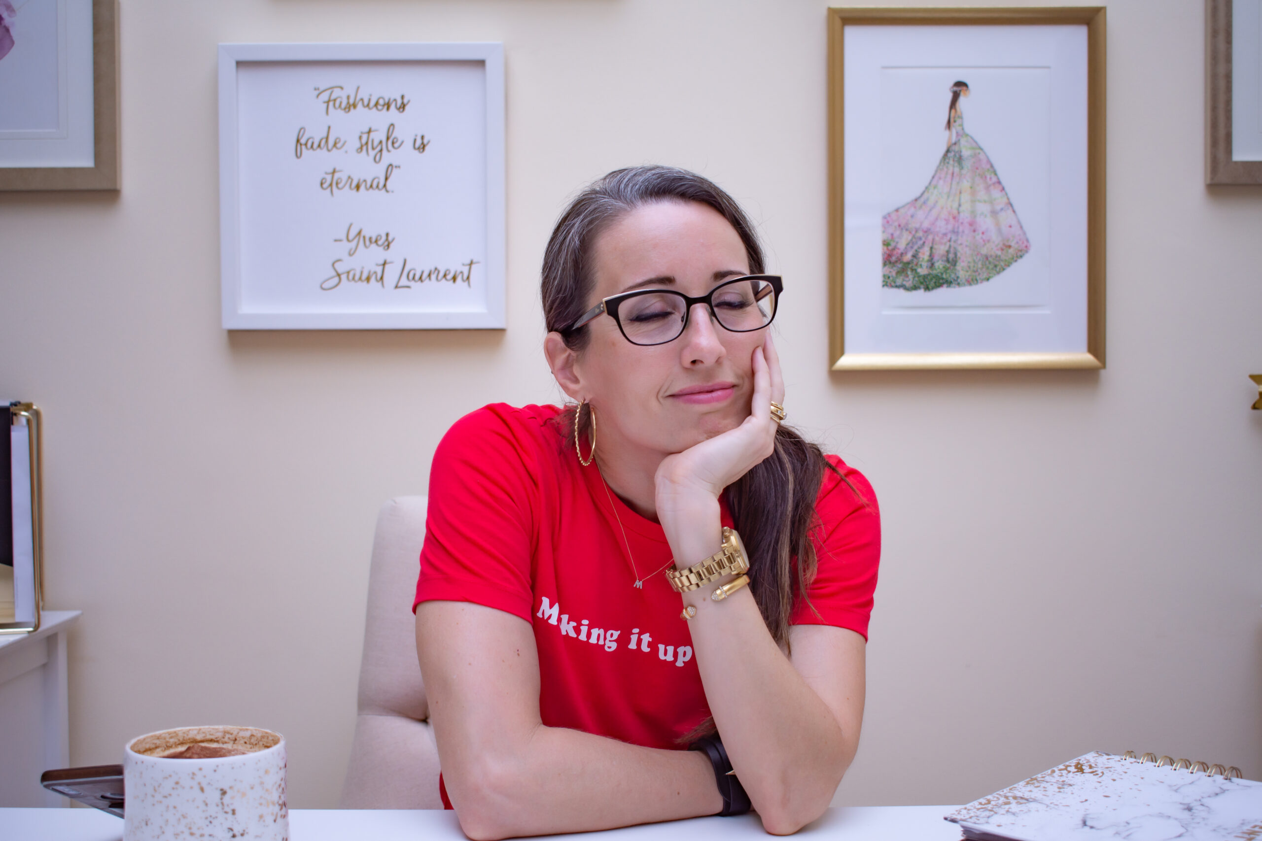 A woman sitting at a table with her chin resting on her hand.