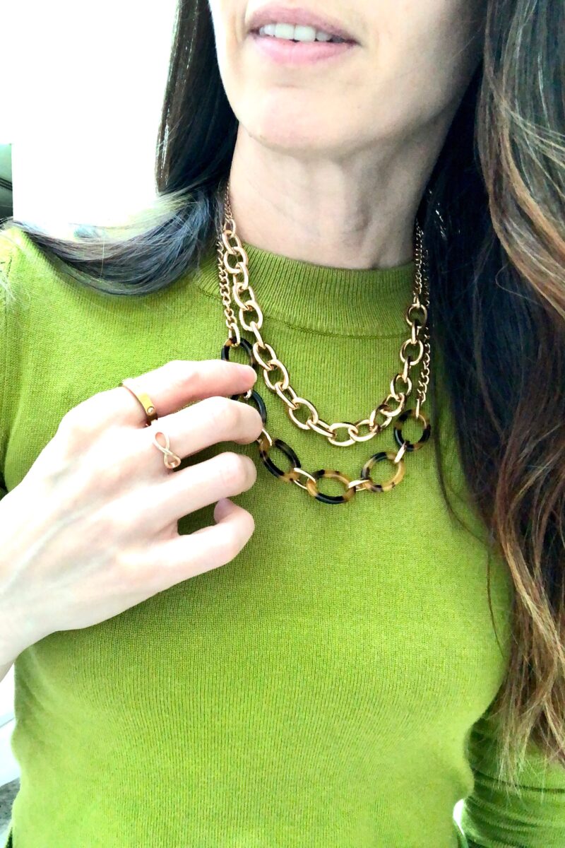 Close up of my chartreuse sweater, gold chain, gold and tortise shell chain and gold rings