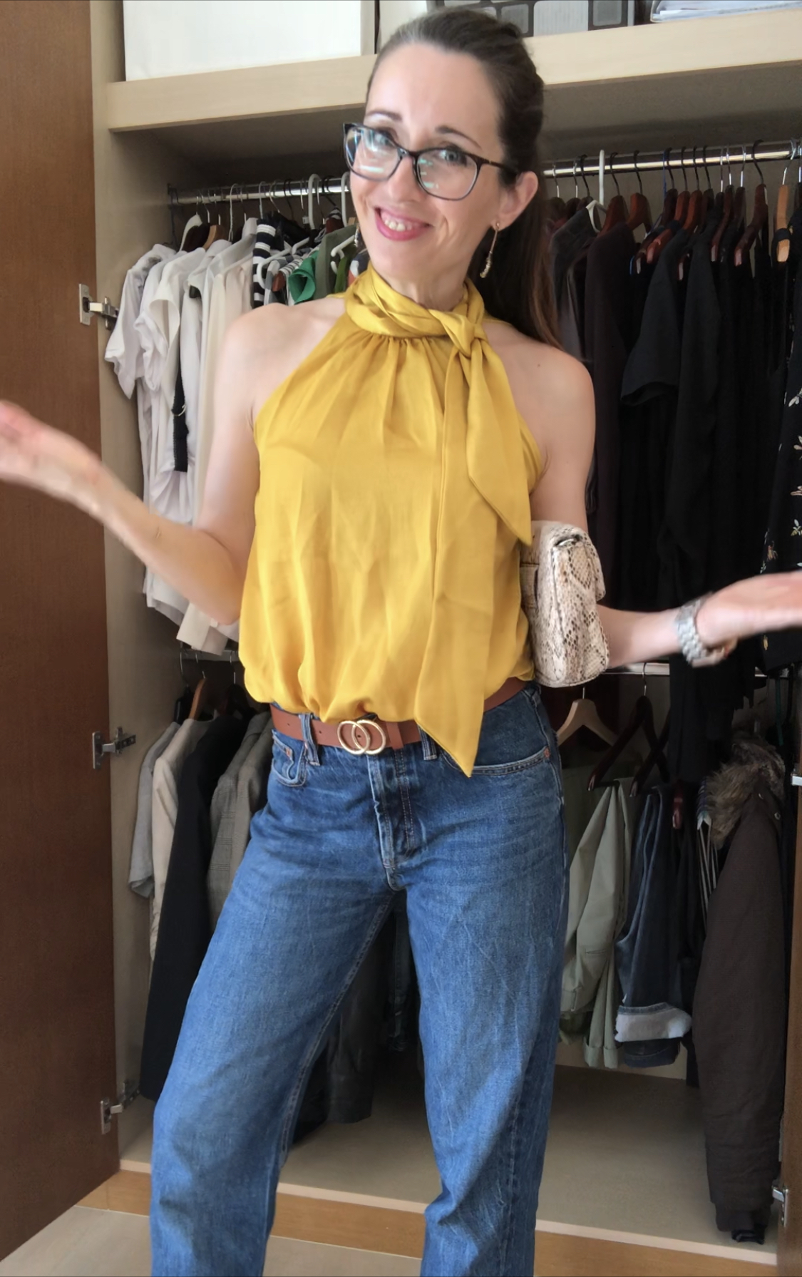 A woman in jeans and yellow top standing next to a closet.