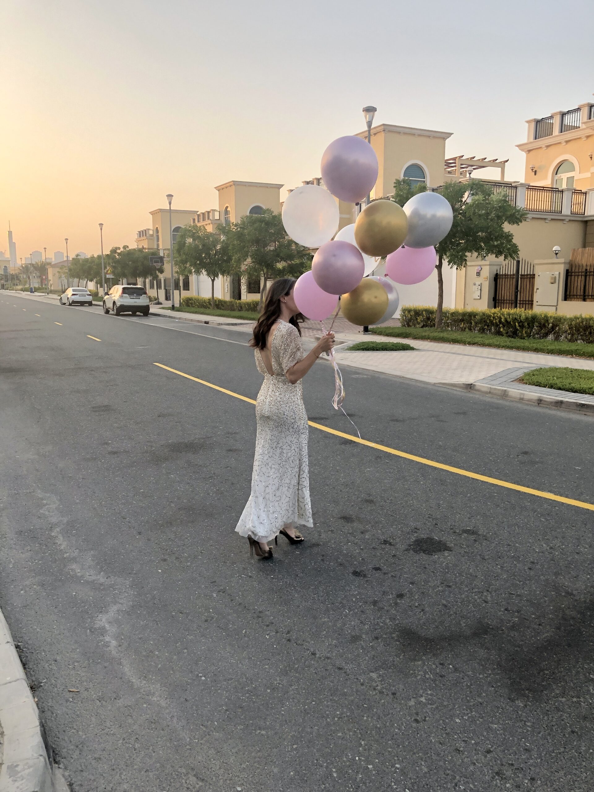 A woman holding balloons while walking down the street.