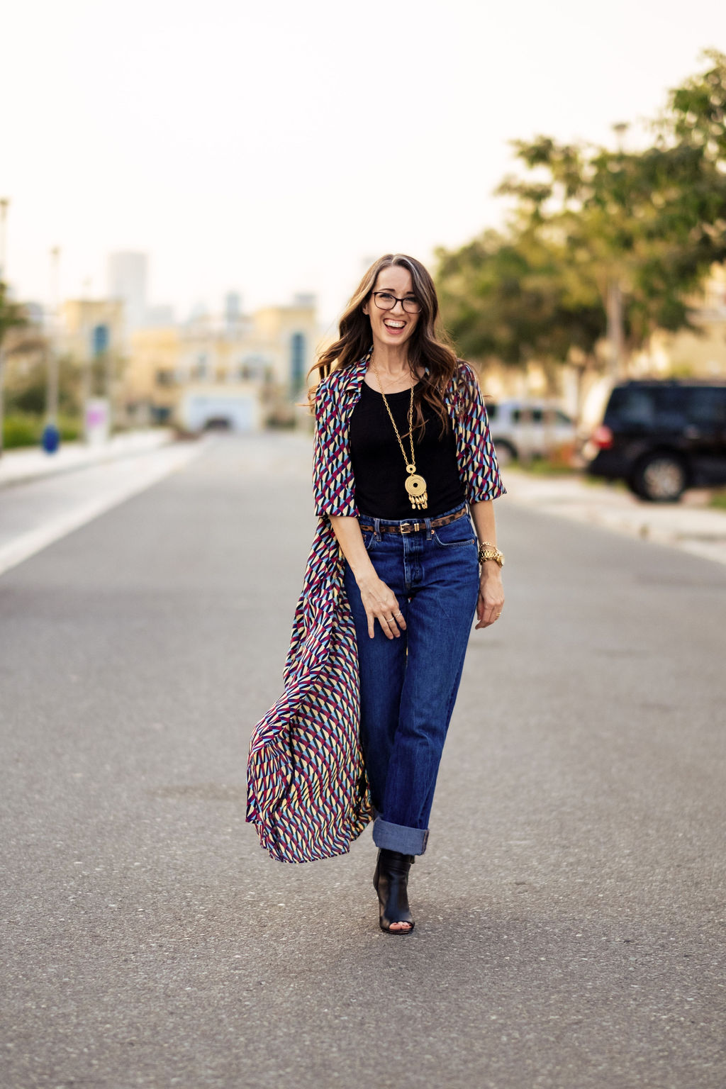 A woman in jeans and boots walking down the street.